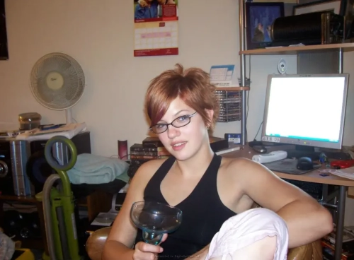 Fiery redhead with long legs poses nude, showing off wet pussy