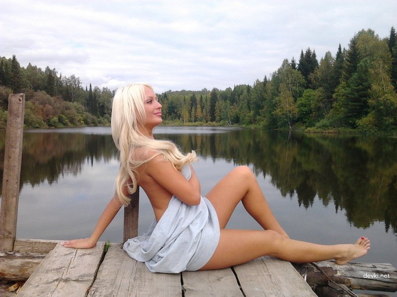 Красивая блондинка позирует голой возле пруда