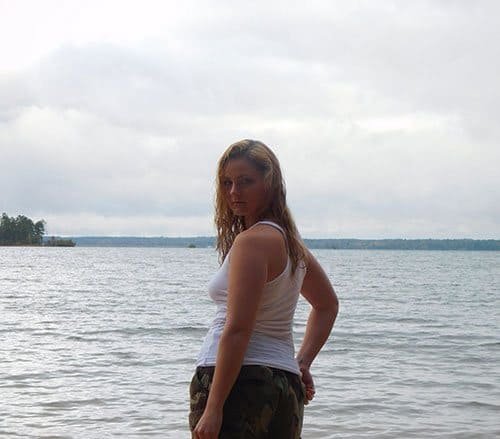 Girl in a wet T-shirt and thong on the shore of a lake
